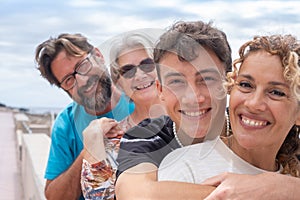 Two mothers and two son of different ages, multi-generation family. Smiling hugging and looking at camera