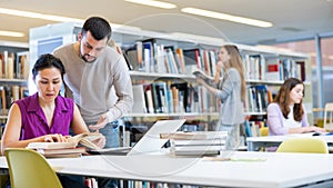 Two male and female students studying together in library