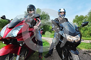 Two motorcyclists standing on country road