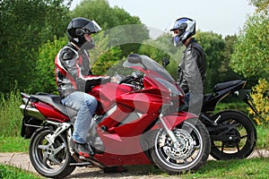 Two motorcyclists standing on country road