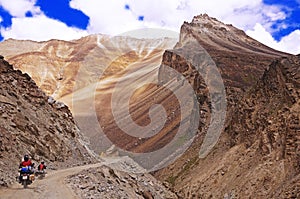 Two Motorcyclists on a Winding Mountain Road in the High-Altitude Mountain Desert in the Himalayas