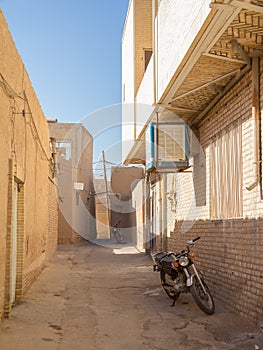 Two motorcycyles standing in a typical street of the old town of Yazd, iran, with its typical clay walls