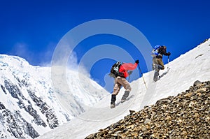 Two mountain trekkers on snow with peaks background