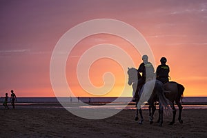 Two mounted Guardia Civil police officers patrolling beach at sunset