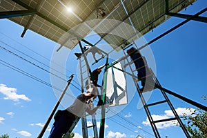 Two mounters installing solar batteries on metallic carcass.