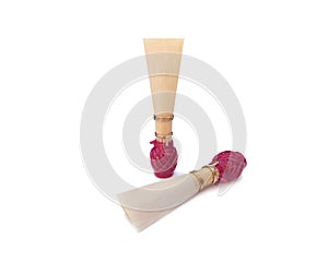 Double reed for bassoon with red thread on a white background.
