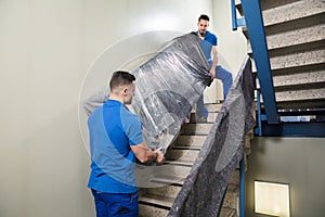 Two Movers Carrying Furniture On Staircase