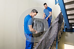 Two Movers Carrying Furniture On Staircase photo