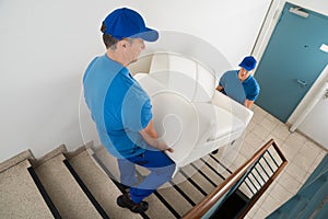 Two Movers Carrying Sofa On Staircase