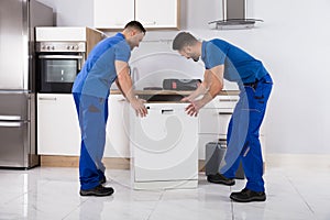 Two Movers Placing Dishwasher In Kitchen