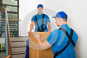 Two Movers Standing With Box On Staircase