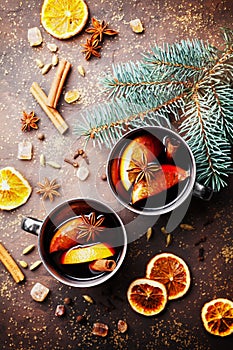 Two mugs of christmas mulled wine or gluhwein with spices and orange slices on rustic table top view. Traditional drink on winter