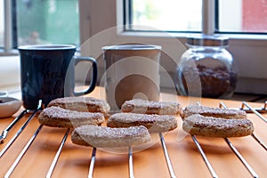 Two mugs of coffee and semilunar sugared cookies on a metal grate photo