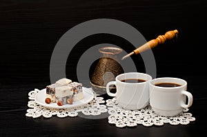 Two mugs of coffee, Turkish lokum with hazelnut, Cezve on a black background