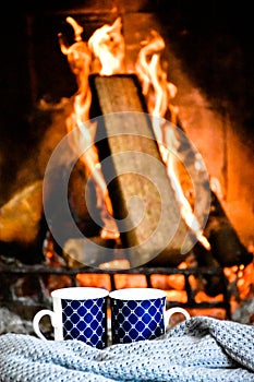 Two mugs (cup) of tea or coffee in front cozy and worm fireplace, in country house.