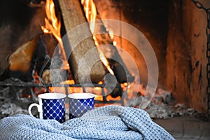 Two mugs (cup) of tea or coffee in front cozy and worm fireplace, in country house.