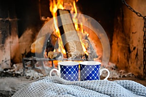 Two mugs (cup) of tea or coffee in front cozy and worm fireplace, in country house.