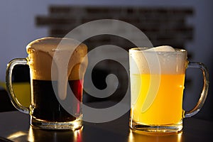 Two mugs of dark and light beer on the bar. International beer day. Culture of brewing in a craft beer store