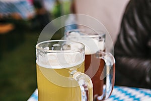 Two mugs with a light and dark beer stand on the table. Celebrating the traditional German beer festival called