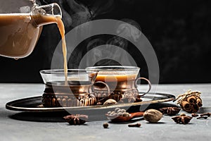 Two mugs of masala tea. Hot indian masala chai tea with milk and spices in a glass glass on dark background. place for text