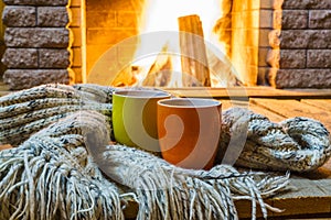 Two mugs for tea or coffee before fireplace.