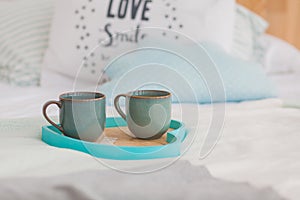 Two mugs on a tray white bed, breakfast concept