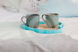 Two mugs on a tray white bed, breakfast concept