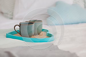 Two mugs on a tray white bed, breakfast concept