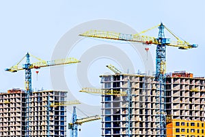Two multi-storey buildings under construction. Many cranes. Construction of modern housing.