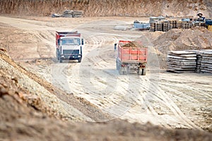 Two multi-ton heavy mining dump trucks empty and loaded during removal of construction soil from construction site