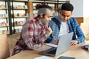 Two multicultural male students studying with laptop