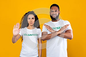 Two Multicultural Volunteers Gesturing Stop Crossing Hands Over Yellow Background