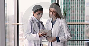 Two multiethnic medical practitioner women walking in hospital hall