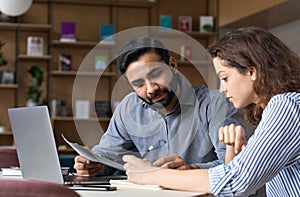 Two multiethnic professionals working together with laptop in office.