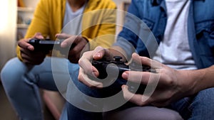 Two multiethnic teenage boys playing computer games at home, hands close-up