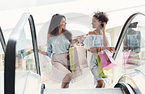 Two multiethnic women on escalator in shopping mall