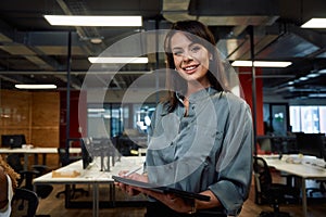 Two multiracial business woman in businesswear smiling while using digital tablet in office