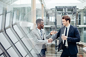 Two multiracial businessmen handshaking in modern office for end of great deal