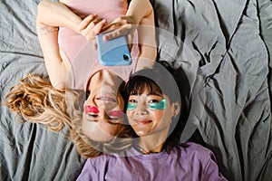 Two multiracial girls in eye patches taking selfie on mobile phone