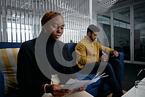 Two multiracial young business people in businesswear reading papers and using digital tablet in office photo