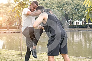 Two muscular men exercising together by a river