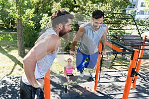 Two muscular young men doing bodyweight exercises in fitness park photo