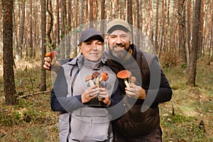 Two mushroom pickers in the forest are holding aspen trees in their hands. Mushrooms in the forest. Mushroom picking