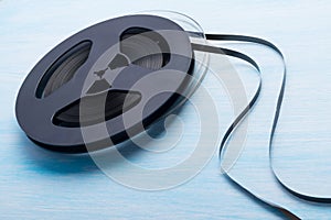 Two musical reels with unwound magnetic film, on a blue table background