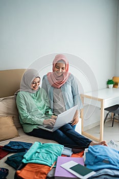 Two muslim woman using laptop to looking departure schedules via online application