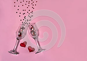 Two narrow empty glasses , red hearts and stars on a pink background. Free space for your text.