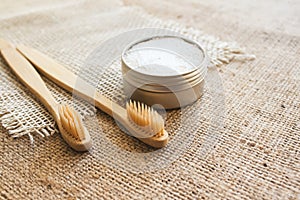 Two natural bamboo toothbrushes and kaolin dentifrice on rustic burlap background with copy space. Sustainable lifestyle and photo