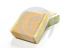 Two natural herbal soaps isolated on white background. Green and yellow aquare shaped products