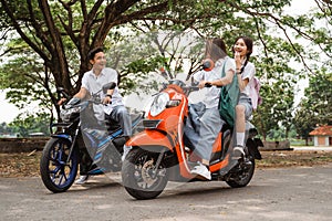 Two naughty high school girls riding motorbikes teasing boy students