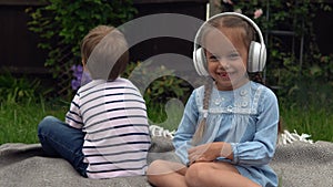 Two naughty Siblings dont share. boy ans girl listening to music on headphones outside. Children and technology. Brother